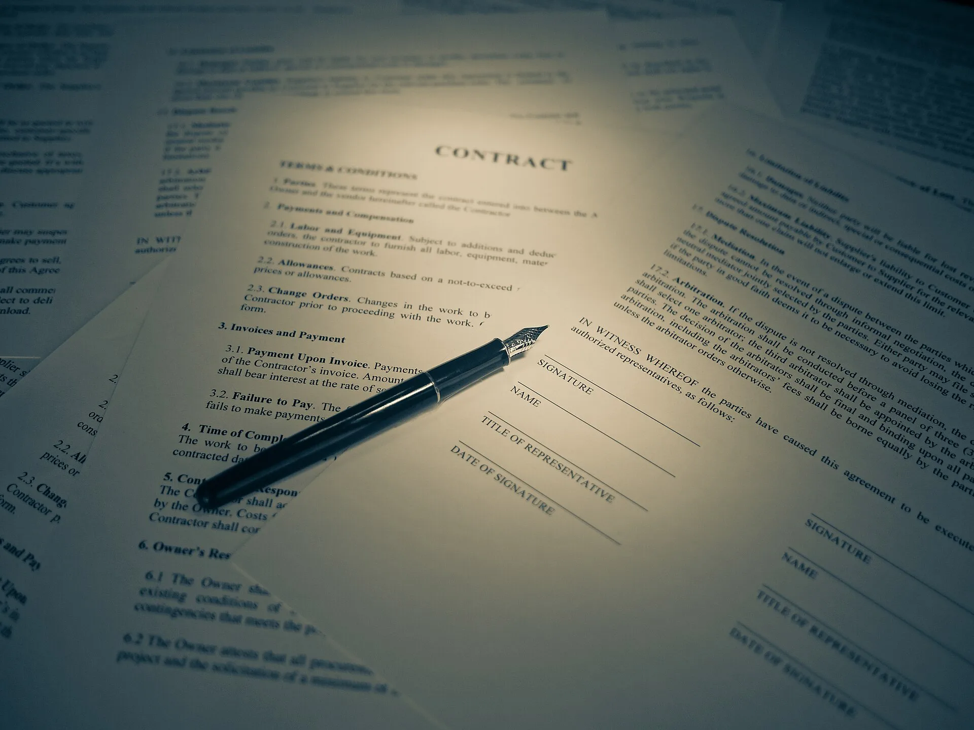 A fountain pen resting on printed contract pages with signature lines.